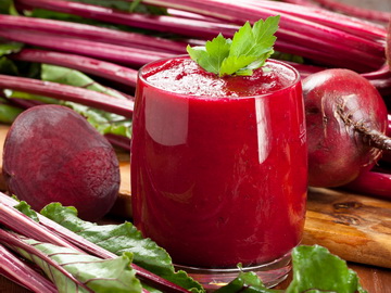 Beets juicing in glass with fresh veggies
